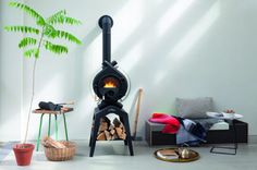 a black stove sitting in the middle of a living room next to a potted plant