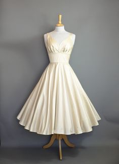 "A romantic and understated 1950's style wedding dress made from a Champagne Silk Dupion with a tea length skirt, perfect for wearing with a layered petticoat for ultimate swish and maximum volume. The fitted waistband creates a fantastic silhouette which echoes the tailored shape of the 50's which is followed through in the full circle skirt. Photographed here with a Swing petticoat underneath for the fuller shape.  Ready to ship NOW This dress is ready made and available off-the-peg in a size Forest Wedding Dress, Dig For Victory, 1950s Wedding Dress, Tea Length Skirt, Full Circle Skirt, Full Circle Skirts, Ivory Dresses, Wedding Dresses Romantic, Tea Length