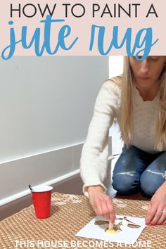 a woman is sitting on the floor and making a painting with her hands while she sits next to a red cup