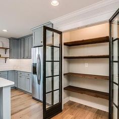 an empty kitchen with open shelving in the center and wood floors on both sides