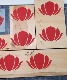 four pieces of wood with red flowers cut out on them, and one piece is being painted