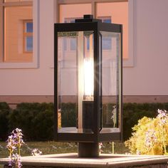 a lamp post sitting in the middle of a flower garden next to a large building