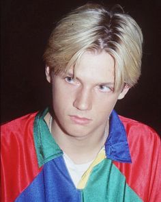 a man with blonde hair wearing a colorful jacket