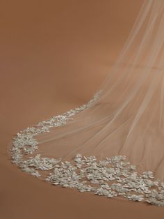 a wedding veil with white flowers on the bottom is shown in front of a brown background