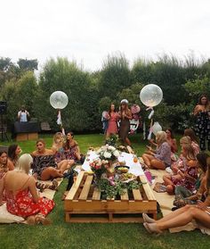 a group of women sitting on top of a lush green field next to each other