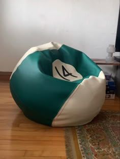 a green and white bean bag chair sitting on top of a hard wood floor next to a tv