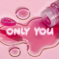 a pink liquid bottle with the words only you on it next to some drops of water