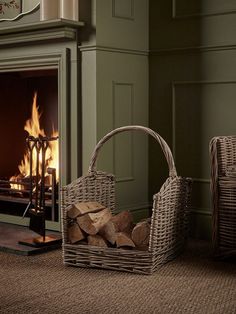 two wicker baskets sitting next to a fireplace with logs in front of the fire