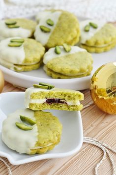 two white plates filled with green and yellow desserts next to an egg on a table