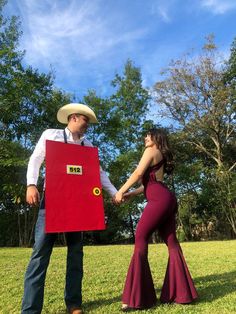 a man and woman dressed up in cowboy hats holding a red box with the word no on it