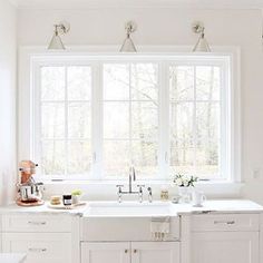 a white kitchen with marble counter tops and gold faucets on the windowsill