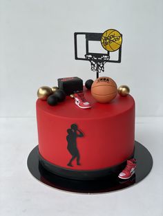 a red cake decorated with basketballs and other sports related items on top of it