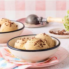 two bowls filled with ice cream sitting on top of a table next to a potted plant