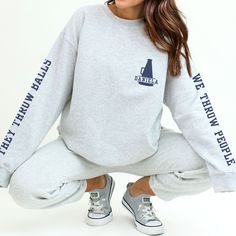 "These cute & funny custom cheer sweatshirts are personalized with each cheerleader's name on the front, and the sleeves are printed with \"They Throw Balls / We Throw People.\"  It's printed just for you on the beloved, buttery soft Gildan 18000 sweatshirt.  These are a relaxed, flattering unisex fit- if you're a looking for a fitted style you may want to size down, for a more relaxed fit go with your usual size, and for an oversized look size up several sizes. Models depicted are approx 5' 8\" Athletic Heather Long Sleeve Top For Fans, Team Spirit Sweatshirt With Relaxed Fit, Team Spirit Long Sleeve Relaxed Fit Sweatshirt, Cotton Tops With Ribbed Cuffs For Fan Merchandise, Game Day Crew Neck Top With Ribbed Cuffs, Team Spirit Crew Neck Top With Ribbed Cuffs, Varsity Style Pre-shrunk Crew Top, Crew Neck Tops For Cheerleading Sports Season, Crew Neck Tops For Cheerleading During Sports Season