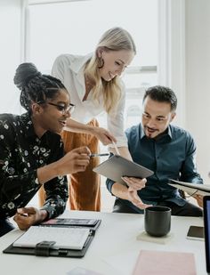 three people are gathered around a table looking at something on a clipboard in front of them