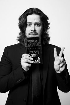 black and white photograph of a man holding a book in front of his face with both hands