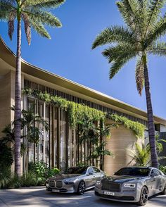 two rolls royces parked in front of a building with palm trees on the side