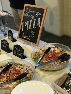 a table topped with lots of different types of food next to a chalkboard sign