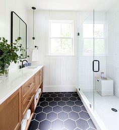 a bathroom with black and white hexagonal floor tiles, wood cabinets, and a large window