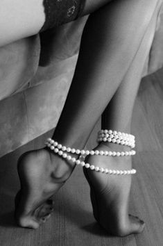 black and white photograph of woman's legs wearing high heels with pearls on them