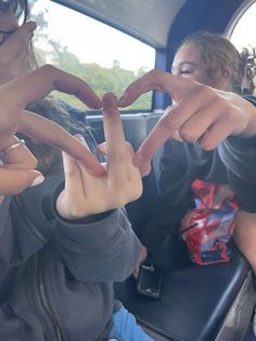 four people sitting in a car making the shape of a heart with their hands and fingers