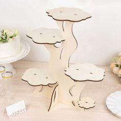 a cake stand made out of wood with flowers on the table in front of it