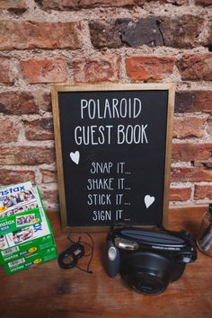 the polaroid guest book is next to its camera and other items on a table