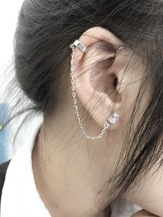 a woman wearing a silver chain ear cuff with two piercings on her left ear