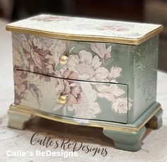 an ornate painted chest with gold trimmings and flowers on the front, sitting on a table