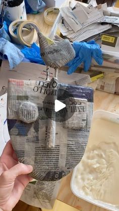 a person holding up a newspaper with the paper cut out to look like a face