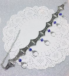 Victorian Gothic metal choker with crescent moon charms and blue crystal beads, ornate metal necklace, Victorian jewelry, Gothic jewelry A beautifully ornate gothic silver metal choker with Victorian crescent moon charms and blue faceted crystal beads. It measures approx. 11 inches in length and has lobster clasp fastening and an extension chain, so that it can be adjusted to fit the neck. The choker is made up of 7 silver toned metal ancient style sections that have intricate detailing. A marve Blue Gothic Metal Necklace, Gothic Blue Metal Jewelry, Blue Gothic Metal Jewelry, Silver Fantasy Choker Adjustable, Adjustable Silver Fantasy Choker, Silver Festival Choker With Moon Charm, Bohemian Silver Choker With Jewels, Ornate Metal Choker Jewelry, Blue Fantasy Jewelry For Jewelry Making