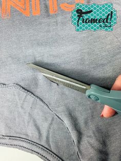 someone is holding a pair of scissors in their pocket to cut the back of a t - shirt