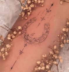 a tattoo on the back of a woman's arm with flowers and arrows in it