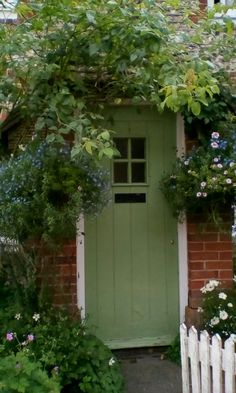 a green door surrounded by flowers and greenery