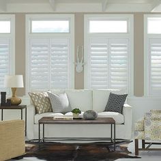 a living room filled with furniture and windows covered in white shuttered glass coverings