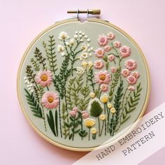 a hand embroidery pattern with pink and yellow daisies on a light green circle frame