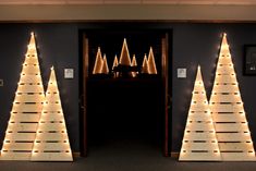 lighted christmas trees in front of an open door with lights on the top and bottom