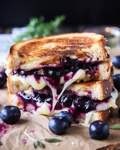 a grilled cheese and blueberry sandwich on wax paper with fresh berries around it