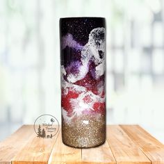 a glass vase sitting on top of a wooden table covered in stars and galaxy paint