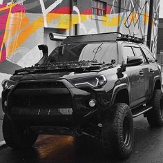 a black and white photo of a truck parked in front of a graffiti covered building