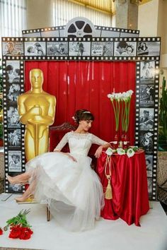 a woman sitting on top of a chair next to a red table covered in flowers