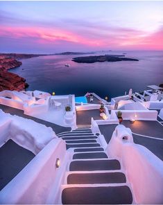 the stairs lead up to an outdoor swimming pool at dusk, overlooking the ocean and cliffs