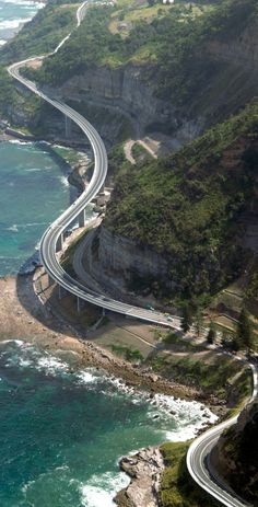 an aerial view of a highway near the ocean with waves crashing on it's sides