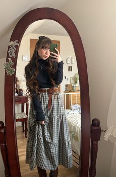 Girl with long wavy brown hair and a bow takes mirror selfie in vintage oval wooden mirror. She is wearing a three tiered dark green plaid maxi skirt with a brown buckle belt and a black long sleeve turtleneck and brown combat boots Cute Cottagecore Outfits Winter, Architecture Outfit Style, Cottage Core Womens Fashion, Easter Vigil Outfit, Cute Winter Skirts, Cottagecore Outfits Work, Midwest Fashion Outfits, Cozy Cottage Core Outfit, 50s Clothing Style