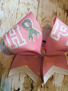 "This bow is made with a 3\" pink grosgrain ribbon with white glitter lettering and a rhinestone center. Other variations are also available. This can also be done in different colors if desired. Bow measures approx 7x7" Cheer Bow Ideas, Pink Cheer Bows, Wonderland Outfit, Alice In Wonderland Outfit, Sideline Cheer, Cheer Things, Cheer Team Gifts, Bow Season, Softball Bows