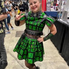 a woman dressed in green and black posing for the camera with her hands on her hips