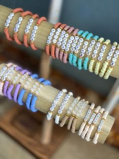 several different colored bracelets are hanging on a wooden rack in front of a window