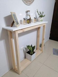 a white table with some plants on top and a clock above it in the corner