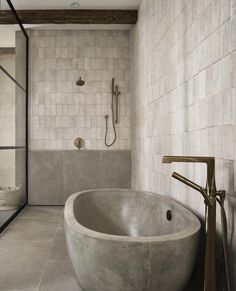 a bath tub sitting next to a shower head in a bathroom with white tile walls