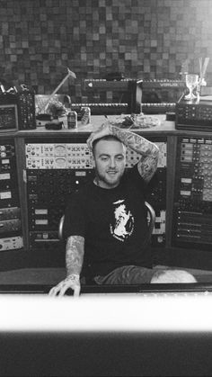 a man sitting in front of an array of sound equipment with tattoos on his arms